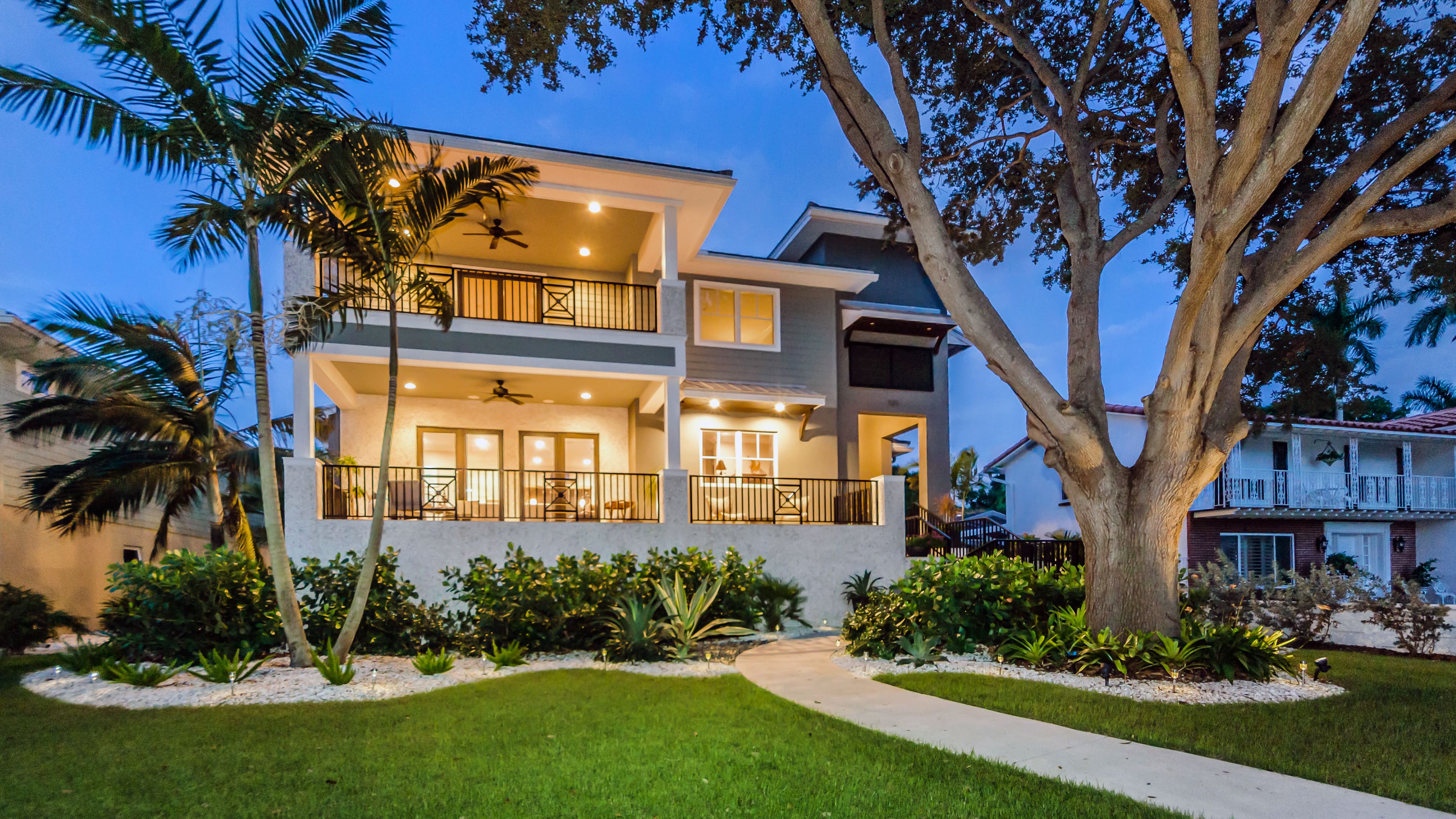 Picture of a luxury house with a large tree in the front yard.